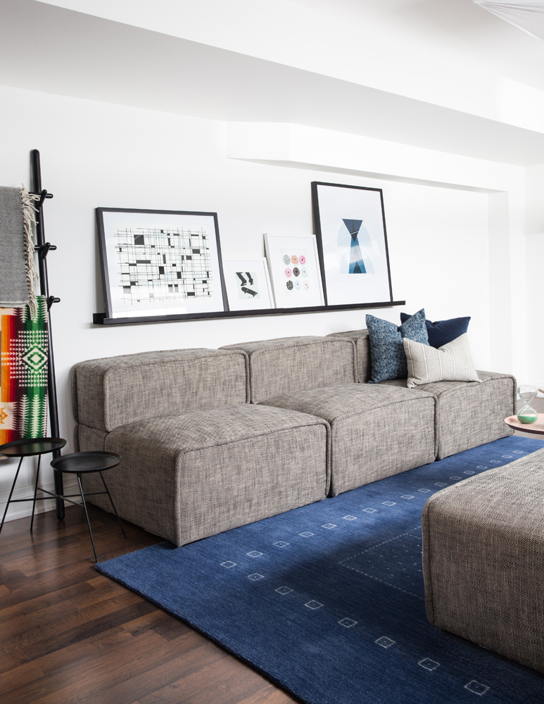 Basement seating with three-section grey sofa and floating shelf with art