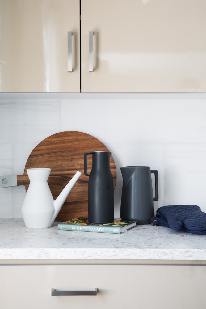 Kitchen counter with round cutting board and black and white jugs
