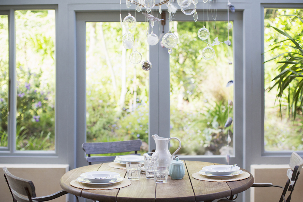 A bright sunroom with glass light fixture and wooden tables and chairs