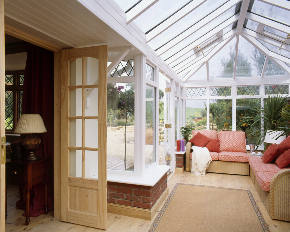 A conservatory-style sunroom with plenty of seating places with colourful wicker couches
