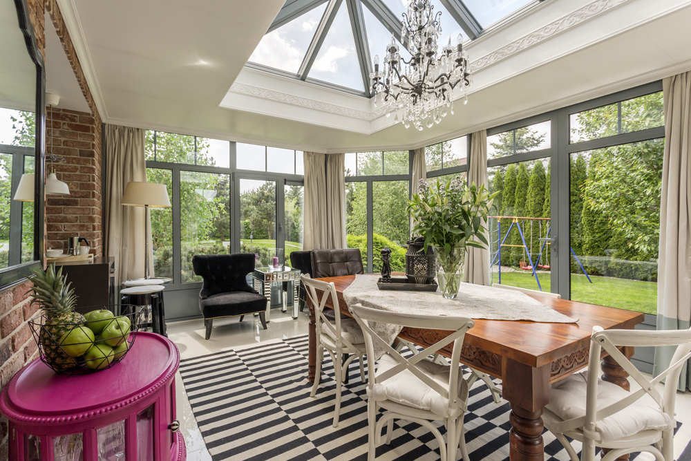 A large sunroom with skylight and furniture in bright colours and textures