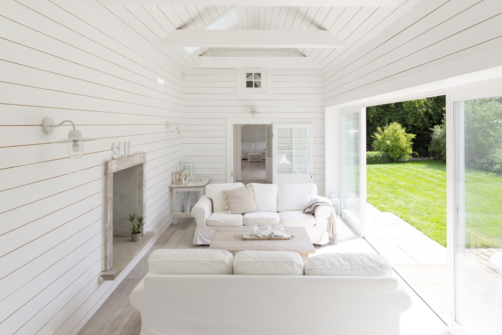 Stark white sunroom with built-in stone fireplace and wide glass sliding screen doors