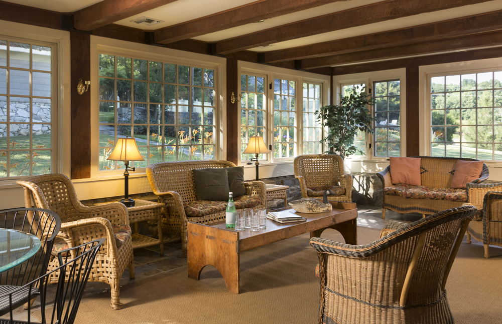A rustic sunroom interior with lots of wicker furniture and various decor pieces that provide texture