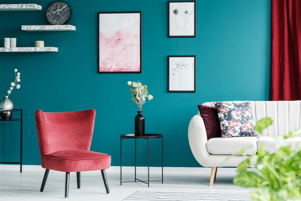 Red armchair, white sofa, paintings and black table in a green living room interior