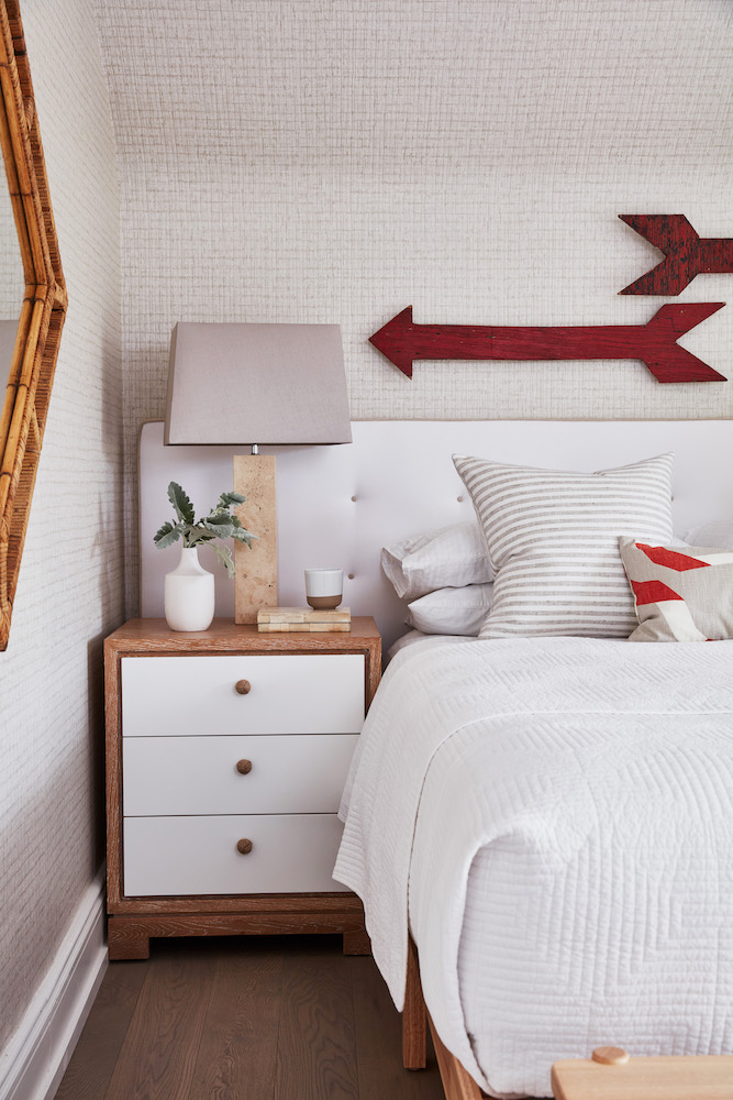 Two vintage red wooden arrows formerly used at a farmhouse are now decorative pieces above the bed