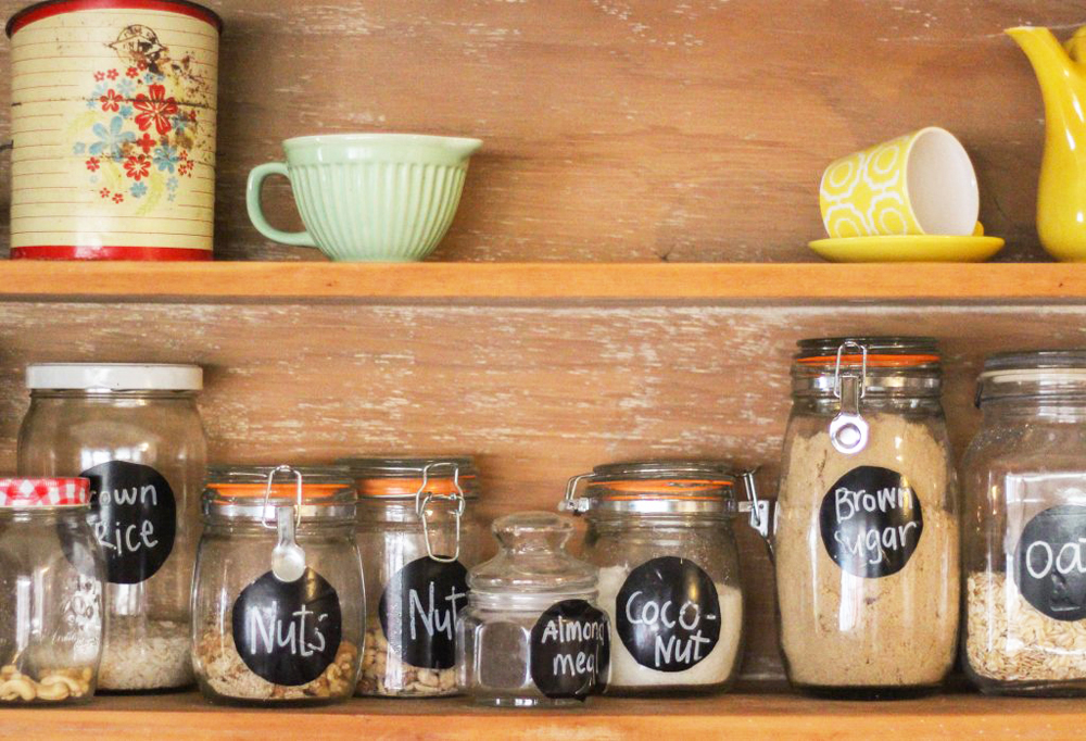 Upcycled jars, canisters, tins and dishware on an open kitchen shelf