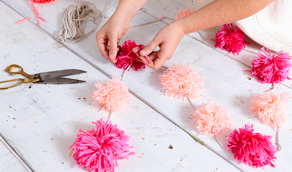 Tiffany Pratt tying DIY pompoms to a string garland