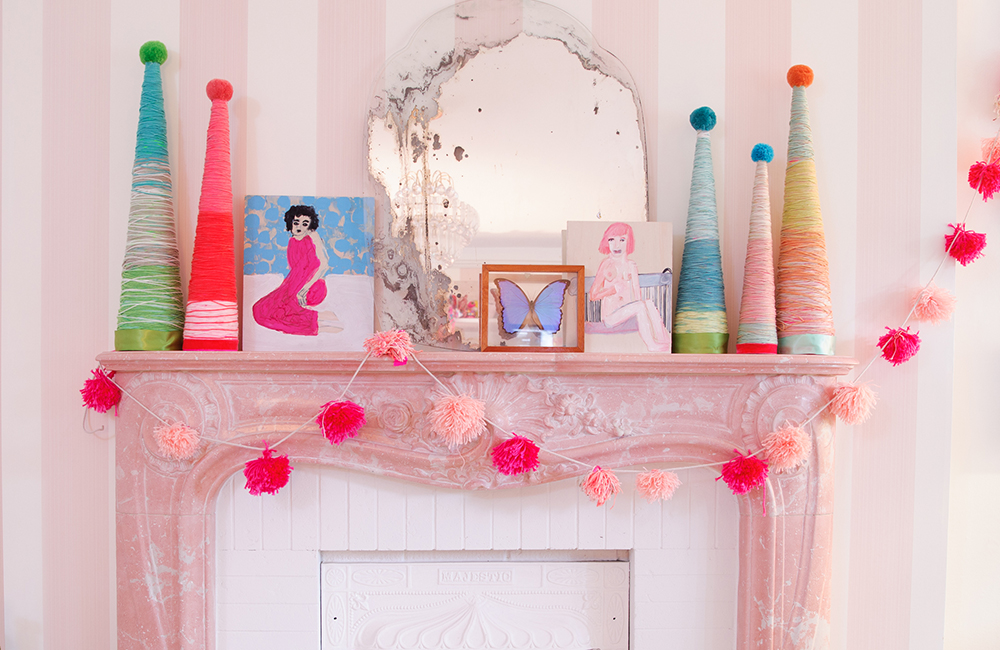 Pink mantle decorated with DIY yarn trees and a pompom garland