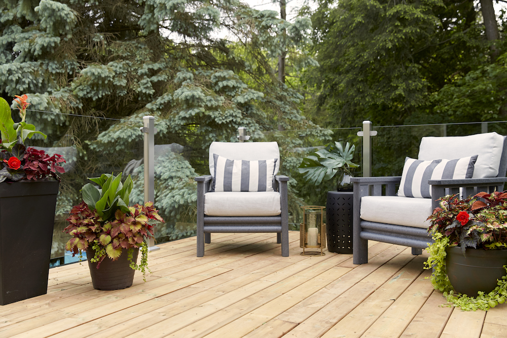 wooden deck with clear glass railings and striped cushions on chairs