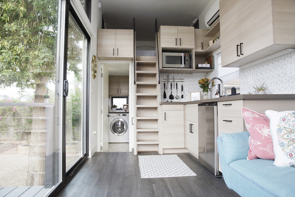interior of a tiny house with large glass windows, showcase the kitchen, living room and loft bedroom
