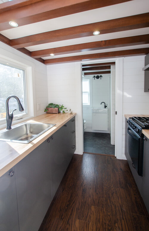 white kitchen with black stove in tiny home