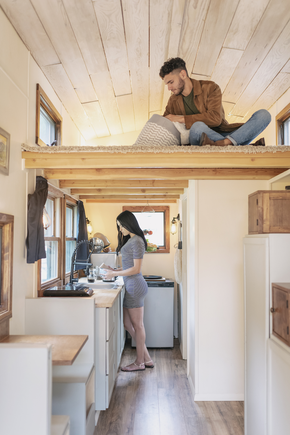 young couple at home in white and wood tiny house interior