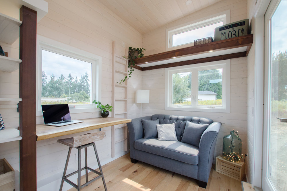 white living room in tiny home with ladder and blue couch