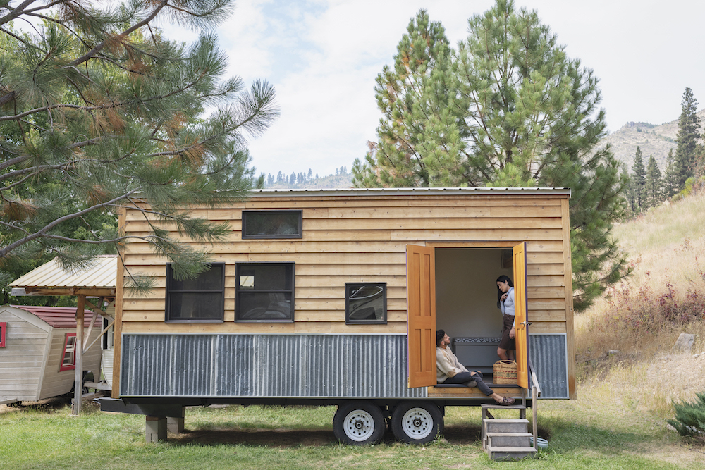 young couple talking in doorway of wooden tiny house