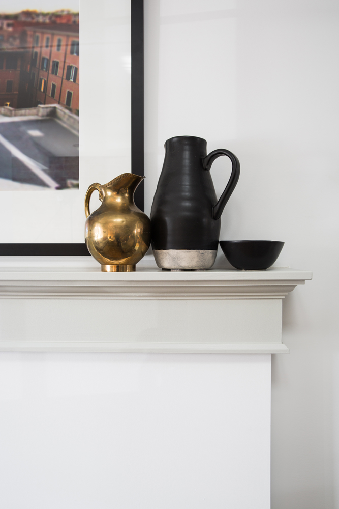 Brass and black jugs on fireplace mantel