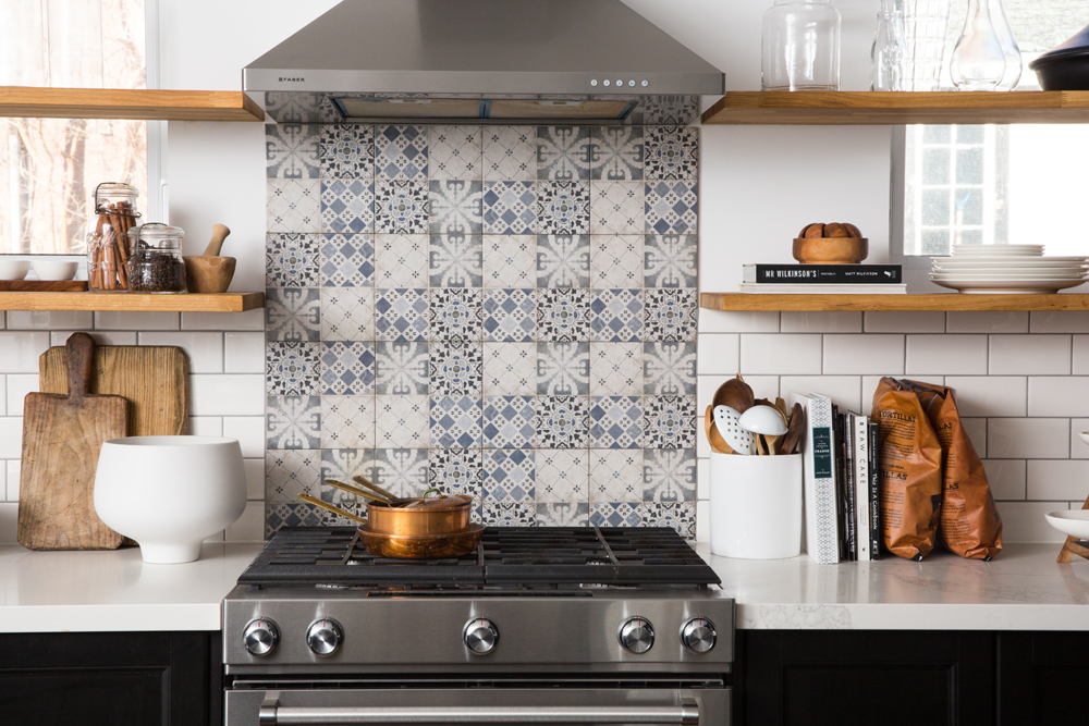 Kitchen with blue patterned backsplash tiles and wood open shelving.