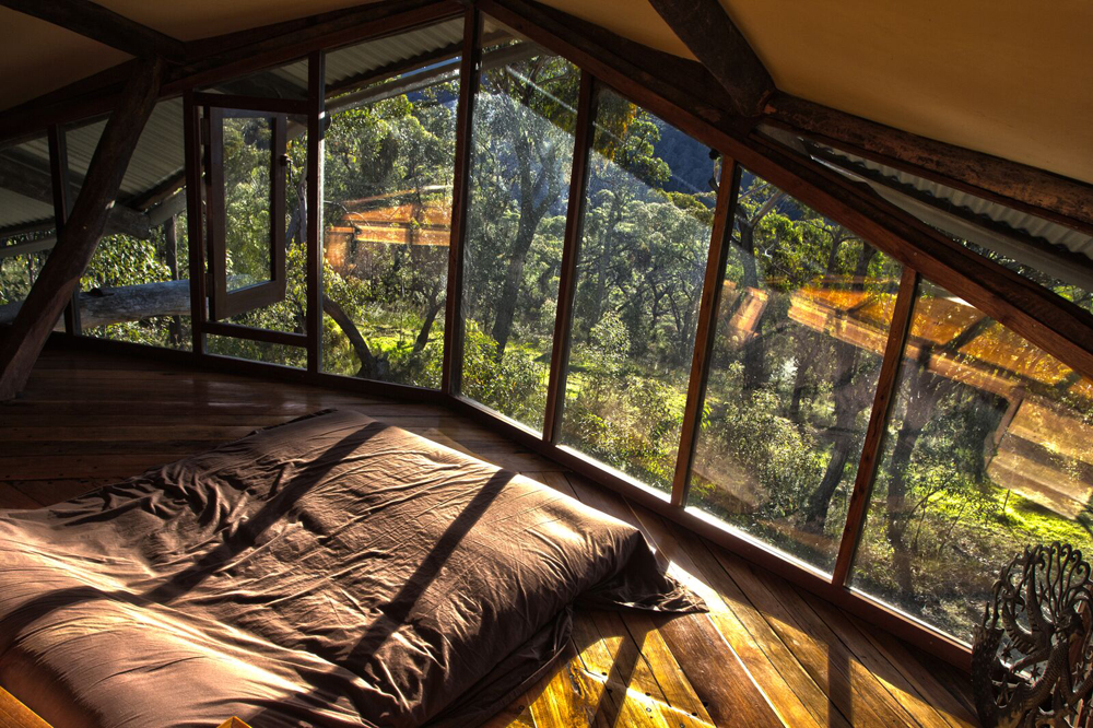 A large mattress on the floor overlooking the view from a large window