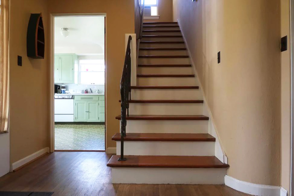 Wooden staircase in the entryway next to the kitchen leading to the second level