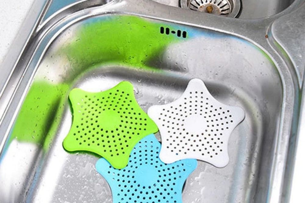 Green, blue and white drain catchers in a stainless steel sink