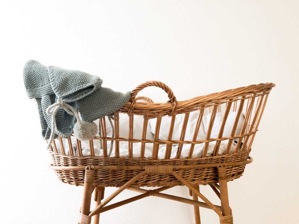 Wicker crib with grey knit blanket in white room
