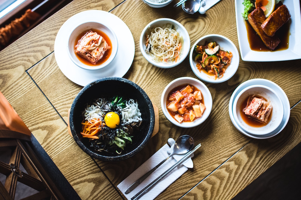 stone dolsot bowl and white bowls filled with Korean food on wooden table