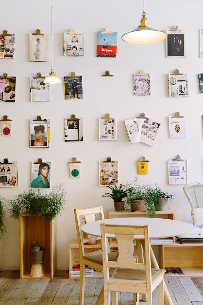 white wall with magazine covers and images on clipboards on wall