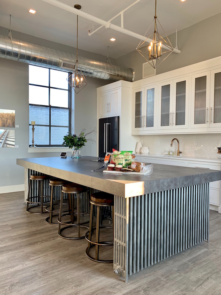 industrial-style kitchen with glass-and-white cabinets and large grey island