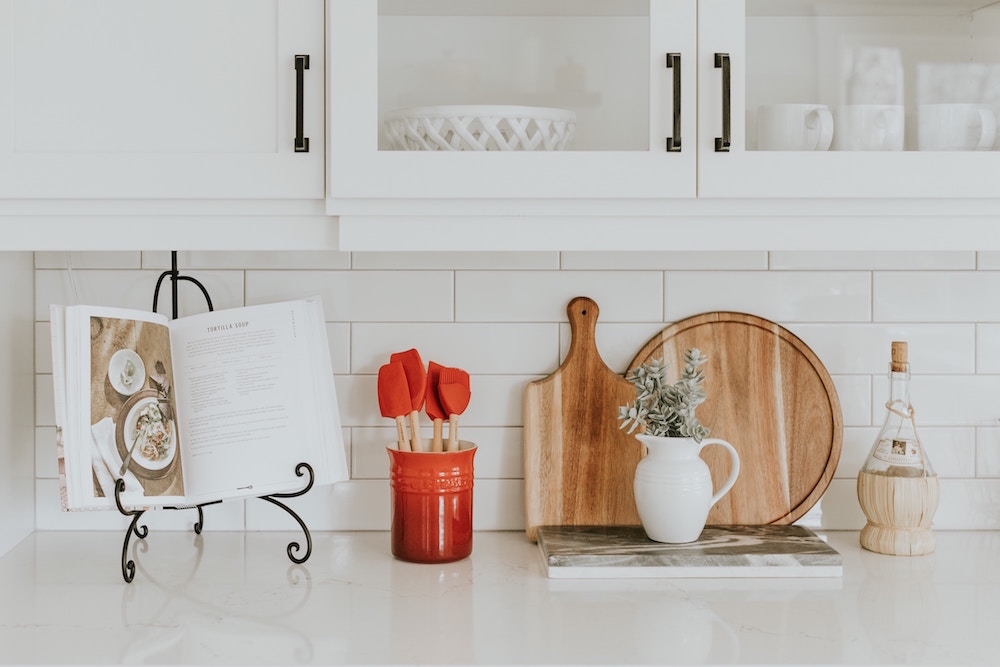 white kitchen with recipe book and wooden cutting boards on counter
