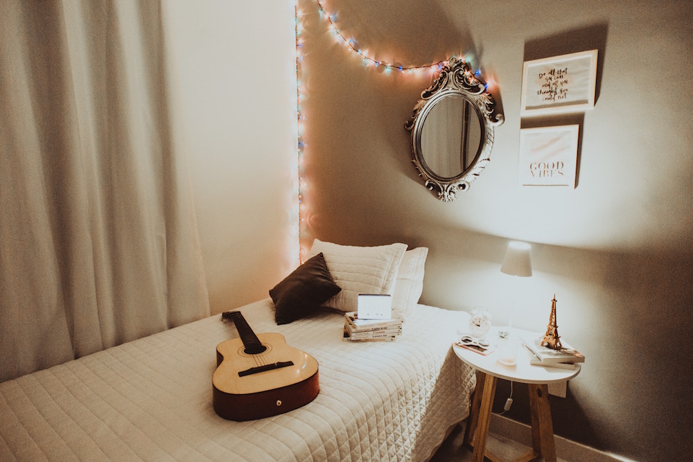 Guitar on white bed in beige room