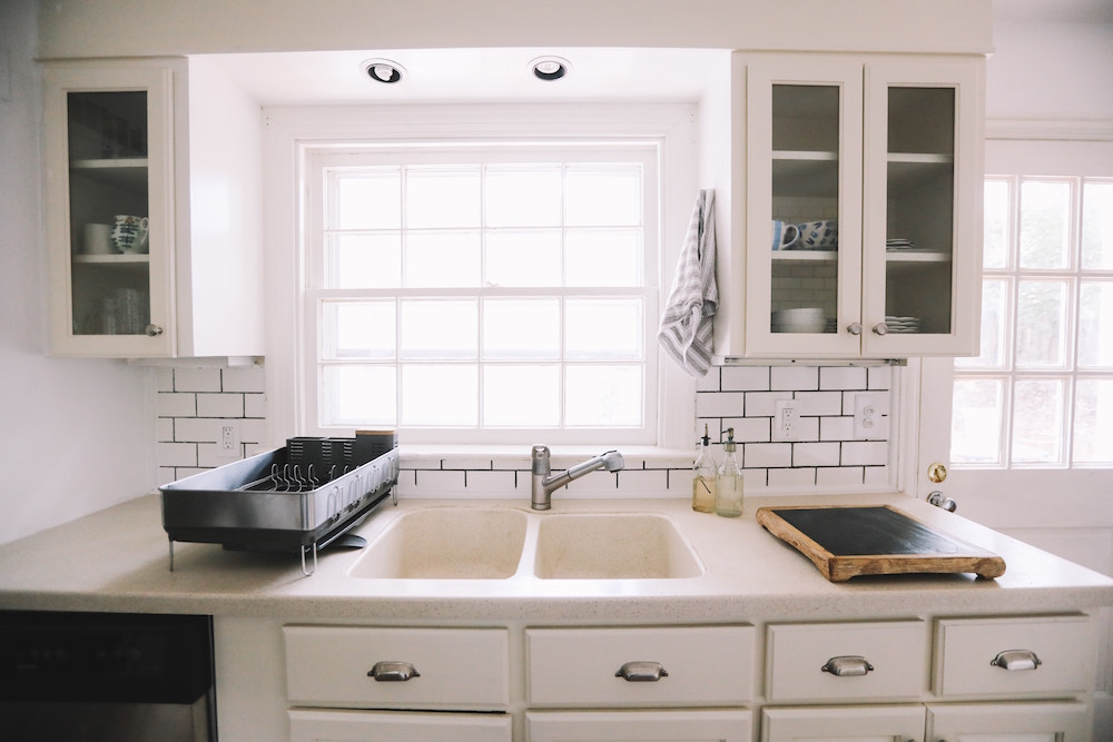 white kitchen with metal dish rack beside white double sink