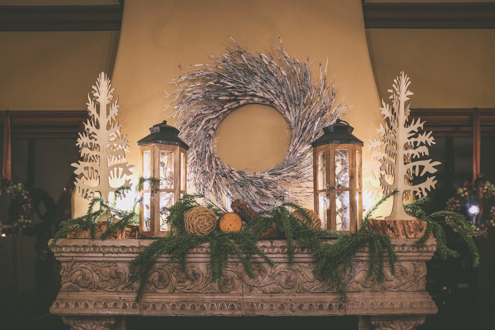 white wreath and wooden decorations on ornate mantle in beige room
