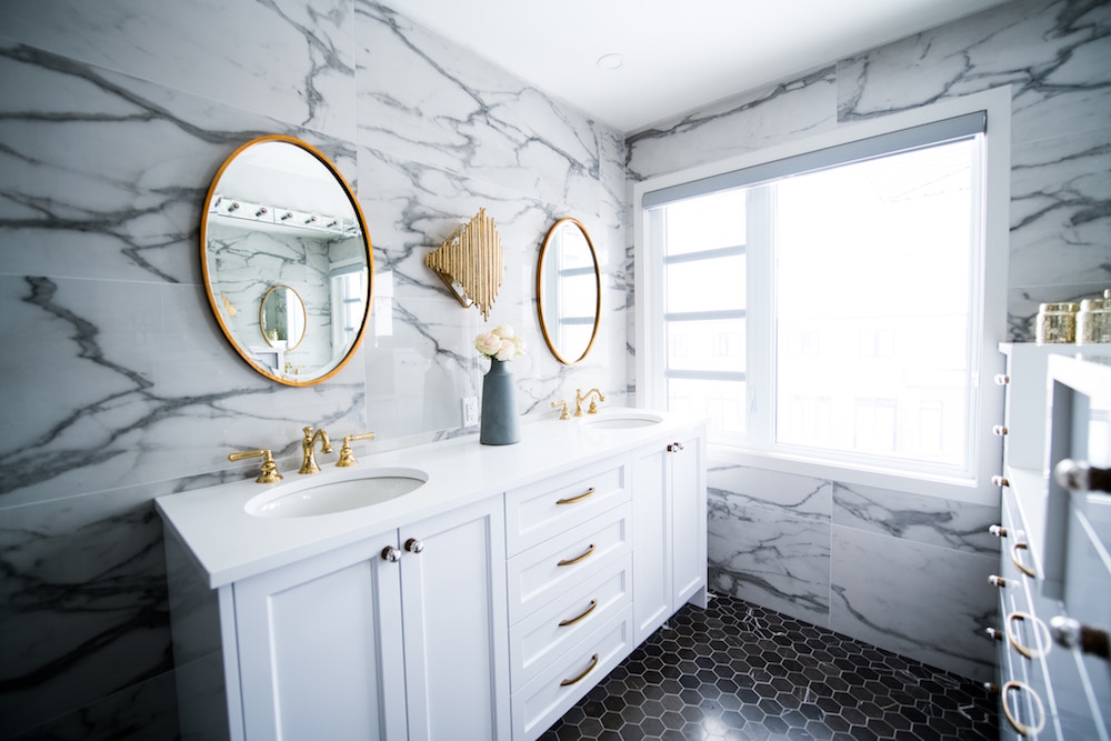 Modern bathroom with marble-tile walls, white vanity and gold hardware