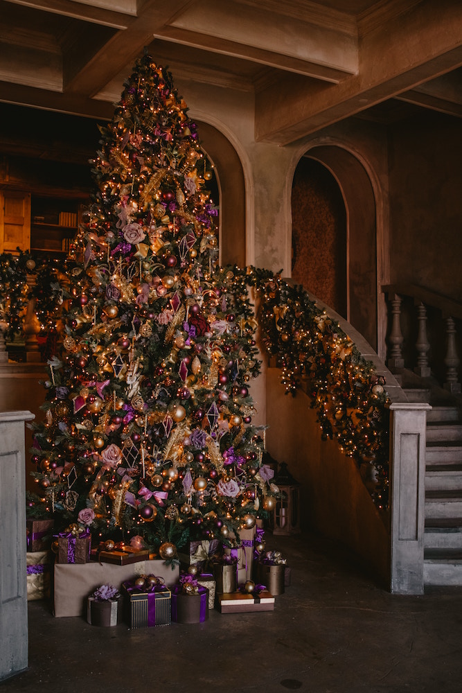 large purple and gold christmas tree beside wooden staircase