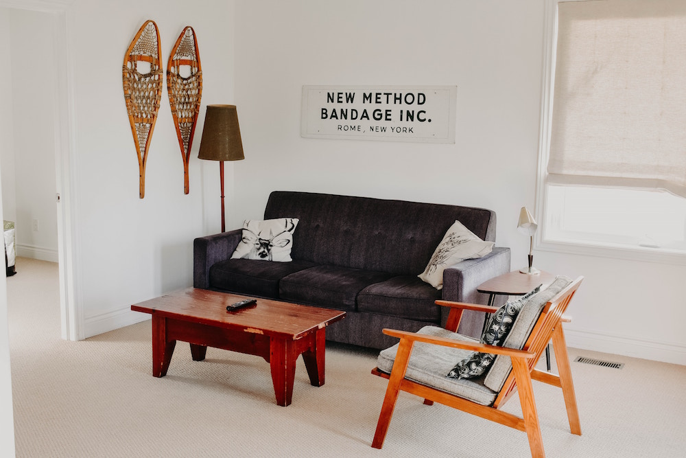white living room with grey couch and snowshoes and sign on wall