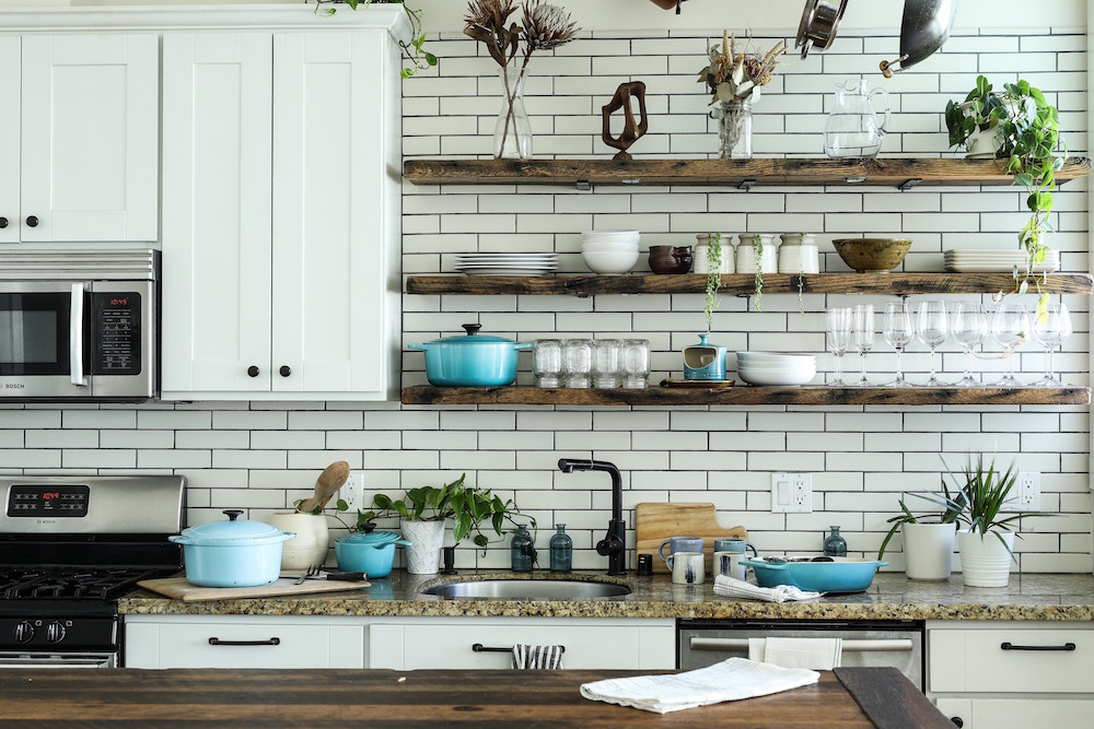 white kitchen with dishes and utensils on shelves and counter