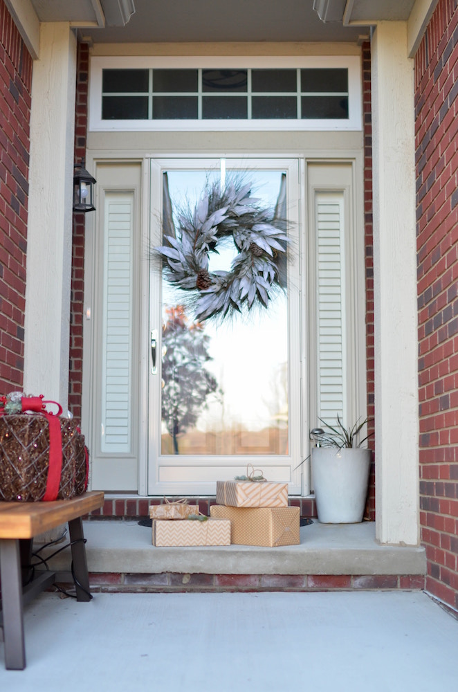 white door with white wreath and brown presents at red brick home exterior