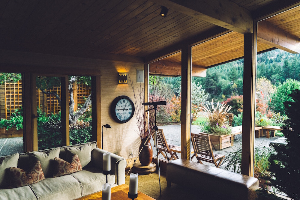 wooden living room with windowed walls and greenery outside
