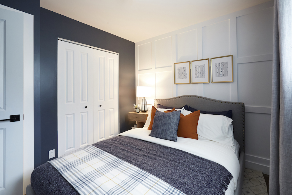 Bedroom with applied moulding feature wall and plaid bedding