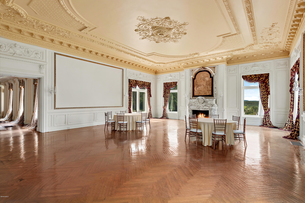 A spacious dining/ballroom area with large windows and marble fireplace