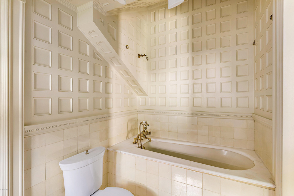 An all-white bathroom with various tiles in different textures and deep soaker tub