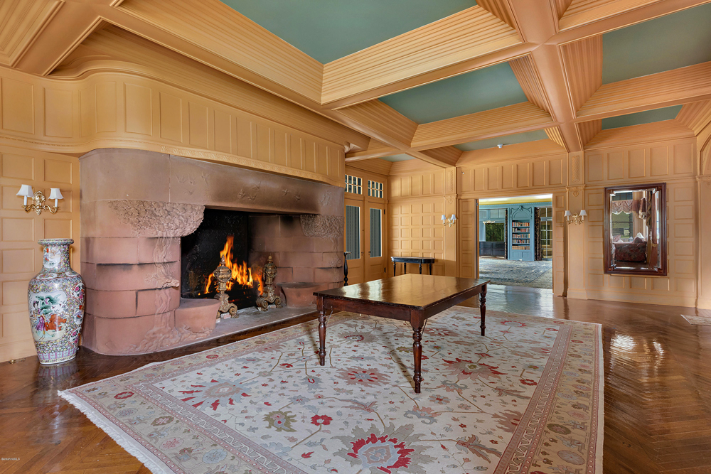 A sitting room with a large wood-burning fireplace and original hardwood flooring