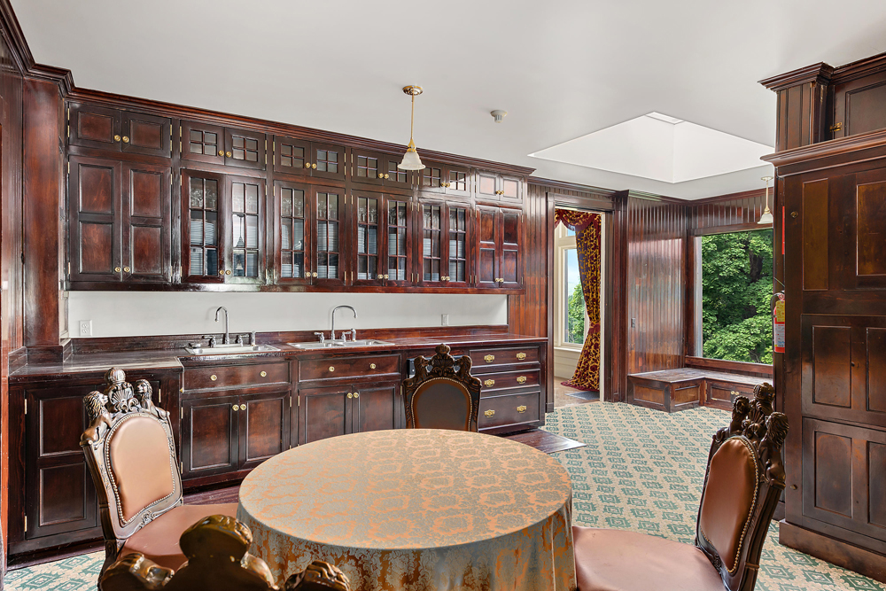 A cherry wood-infused servants kitchen and dining area with carpets and small round table