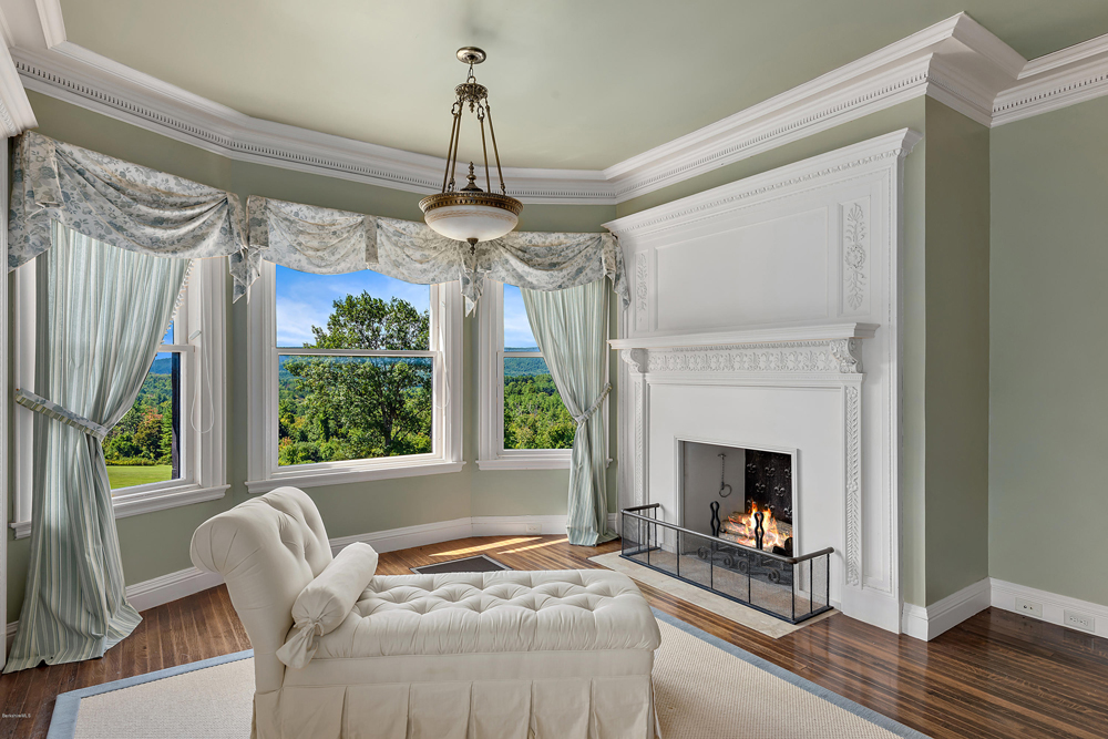 A chaise lounge next to a fireplace in a second level bedroom that overlooks the panoramic views