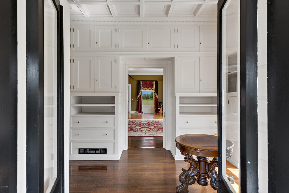White storage cabinets in a hallway leading to various rooms and a door leading outside