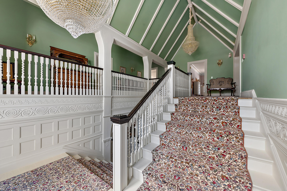 A floral patterned carpeted staircase leading up to the second level, with walls painted in a sage green