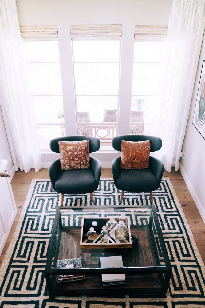 An overhead shot of two teal chairs placed on a large print rug.