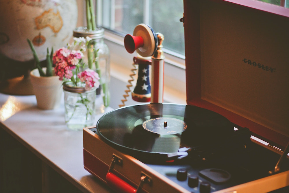 vintage phone, record player and vase on windowsill
