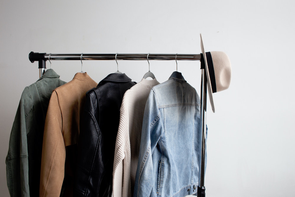 white wall with stylish jackets on clothing rack
