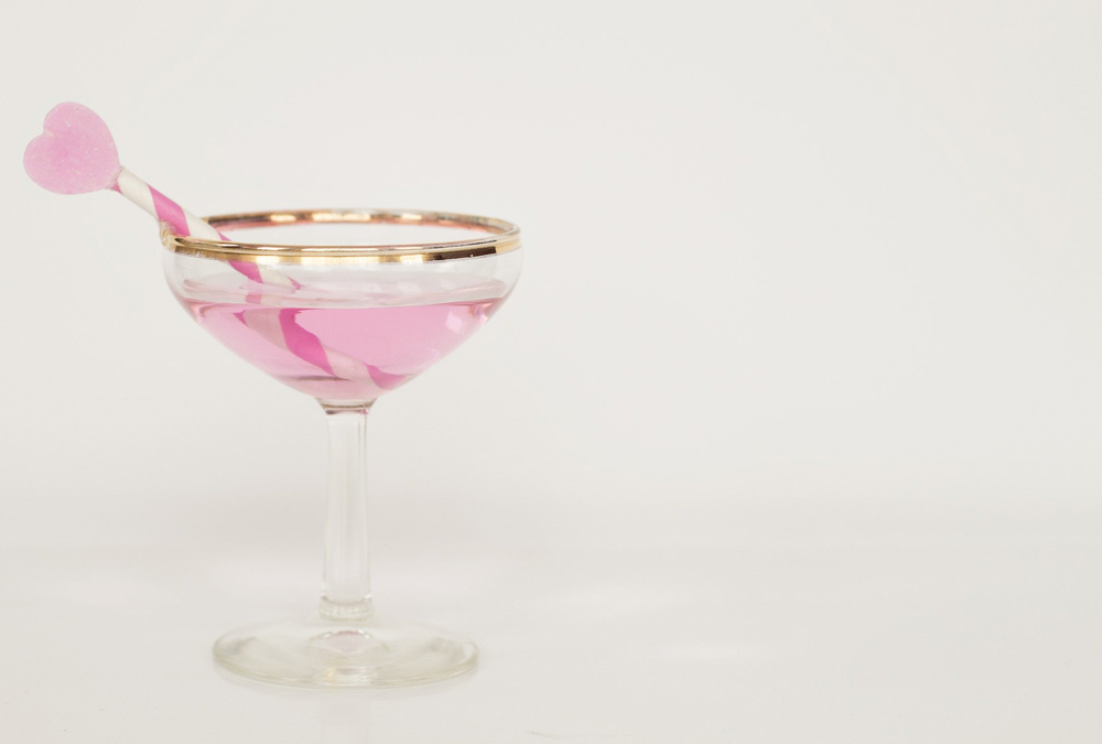 A martini glass with a heart-shaped straw