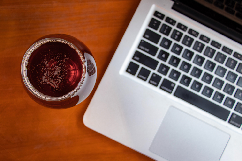 An open laptop with a glass of red wine beside it